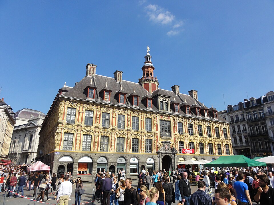 Une rue de braderie bordée de stands, devant la mairie, un matin de septembre