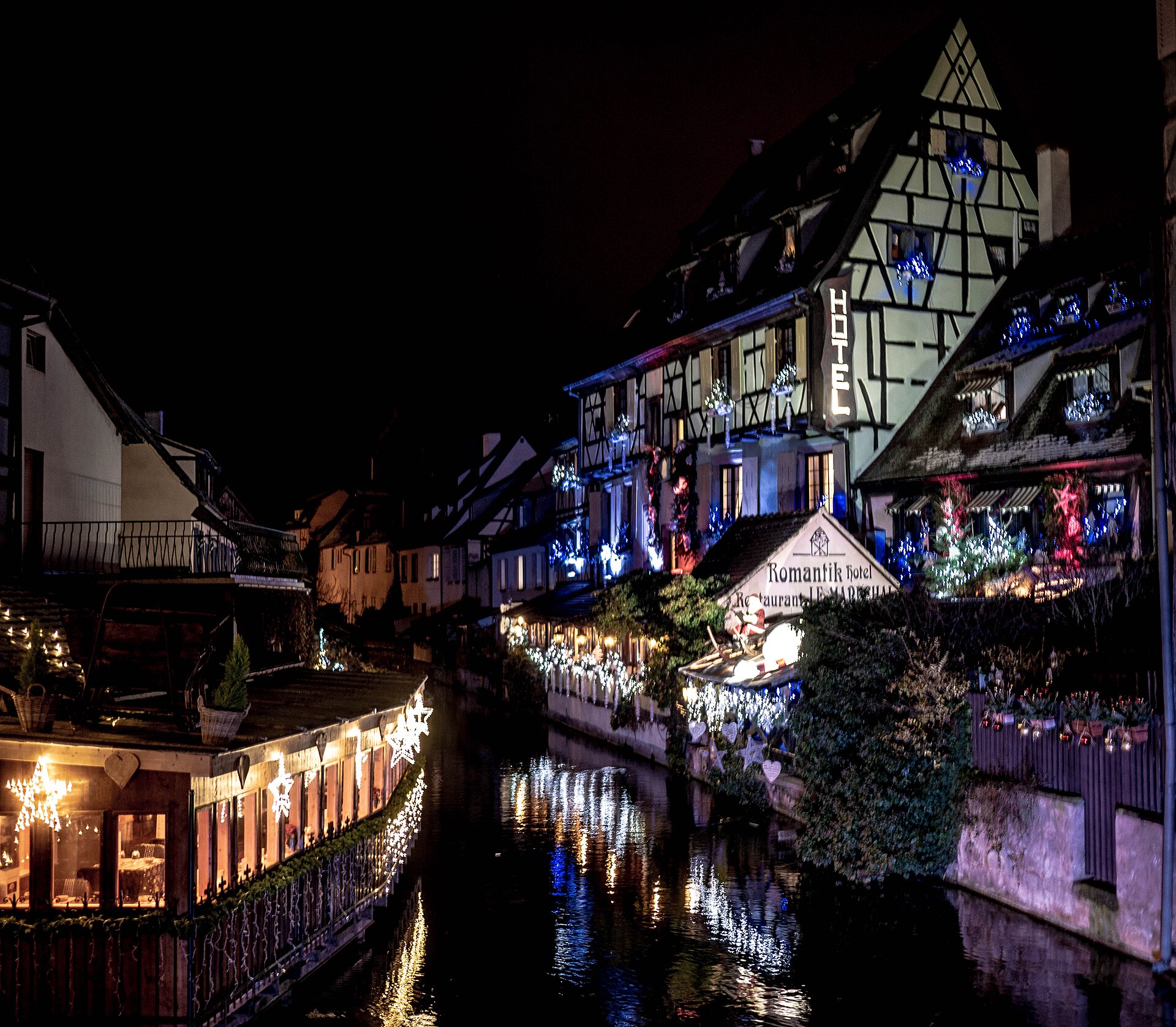 Un canal de Colmar illuminé à la nuit tombée, avec ses maisons à colombages décorées pour Noël